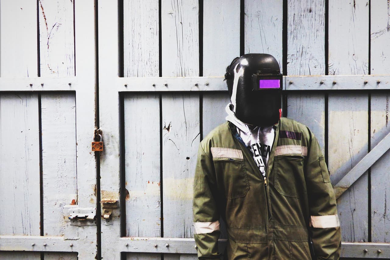 Soldador profesional con casco y uniforme verde